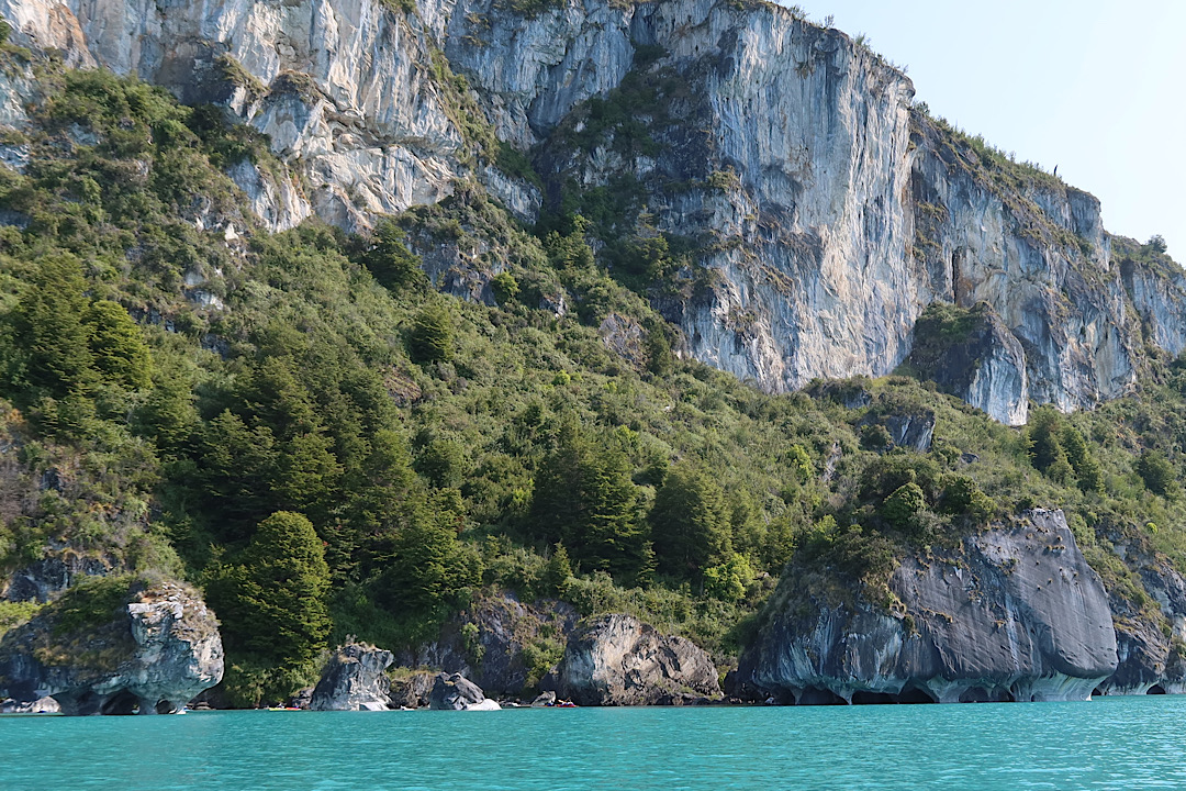 From afar, the caves are nearly invisible at the bottom of giant cliffs.